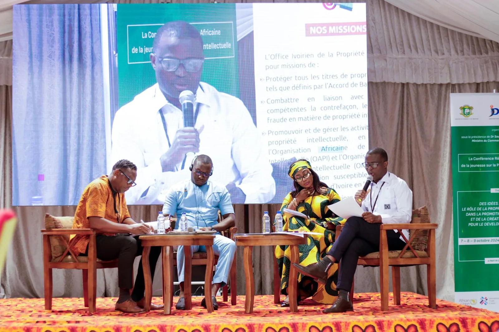 Panelists seated before an event screen